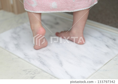 A girl wiping her feet on a diatomaceous earth bath mat 133797342