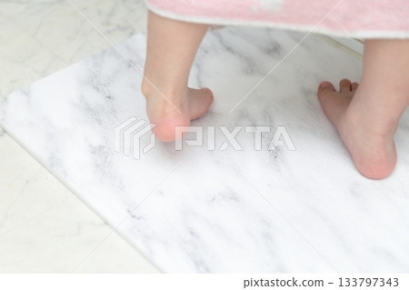 A girl wiping her feet on a diatomaceous earth bath mat 133797343