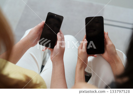 Social Media Connection. Two friends holding smartphones with blank screens. Social Media Connection. Two friends holding smartphones with blank screens. 133797528