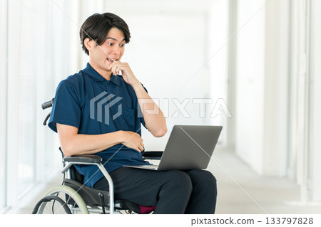 A young Asian man in a wheelchair using a computer (surprised, amazed, surprised, surprised) 133797828