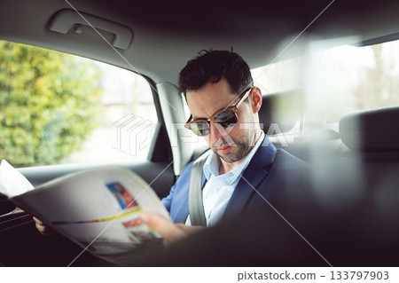 Man reading a newspaper in a car Man reading a newspaper in a car 133797903