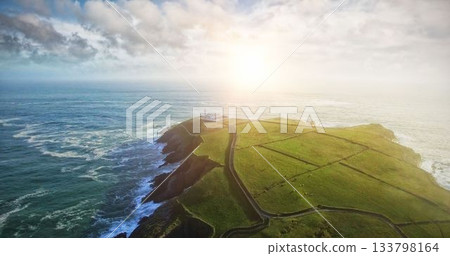 Grassy coastal peninsula in flat design is showing road between stone walls leading to lighthouse Grassy coastal peninsula in flat design is showing road between stone walls leading to lighthouse 133798164
