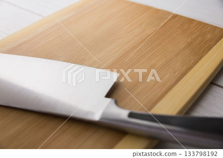 Large knife and chopping board on hardwood floor Large knife and chopping board on hardwood floor 133798192