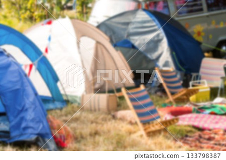 Tents by van and chairs on grassy field 133798387