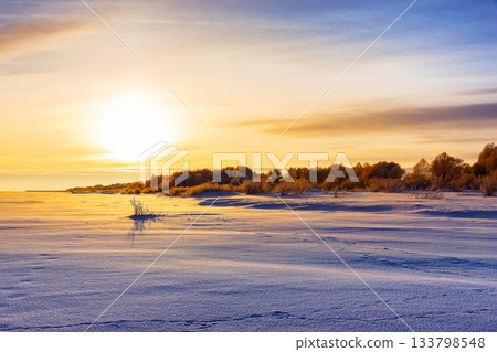 Scenic view of sunset and snow field. Field covered with a snow in cold winter season. Scenic view of sunset and snow field. Field covered with a snow in cold winter season. 133798548