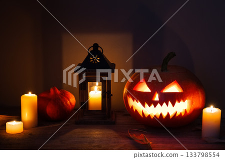Halloween background with pumpkins, lantern, candles and fallen leaves on wooden background. Scary carved halloween pumpkin, jack o'lantern. 133798554