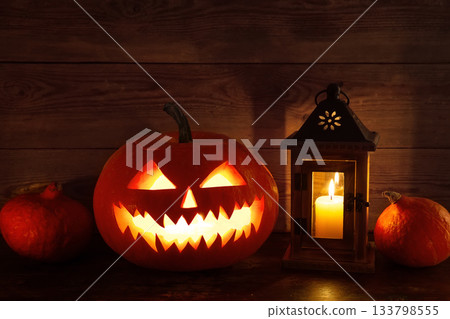 Halloween background with pumpkins, lantern and candles on old wooden background. Scary carved halloween pumpkin, jack o'lantern. 133798555