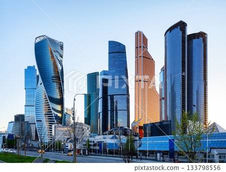 Low angle view of modern business skyscrapers in financial district. Reflective skyscrapers, business office buildings against blue sky. Low angle view of modern business skyscrapers in financial district. Reflective skyscrapers, business office buildings against blue sky. 133798556
