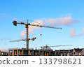 Silhouettes of tower cranes against the blue sky background. House under construction. 133798621