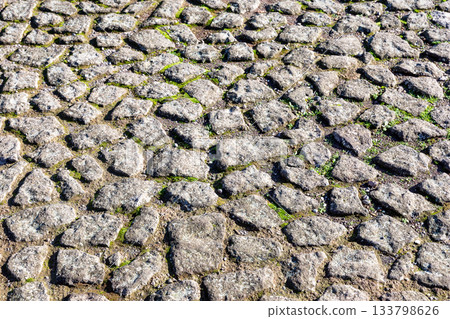Old cobble stone paving perspective background. Paving stone pavement texture. Old stone sidewalk in Rome, Italy. Cobblestone pavement top view. Old cobble stone paving perspective background. Paving stone pavement texture. Old stone sidewalk in Rome, Italy. Cobblestone pavement top view. 133798626