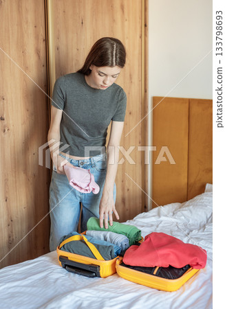 Young woman packing clothes for an upcoming trip Young woman packing clothes for an upcoming trip 133798693