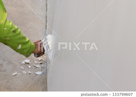 Hand of worker with wall plastering tools renovating house. 133799607