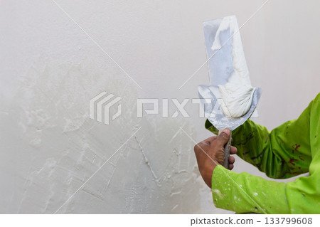 Worker with wall plastering tools renovating house. 133799608