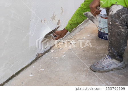 Hand of worker with wall plastering tools renovating house. 133799609