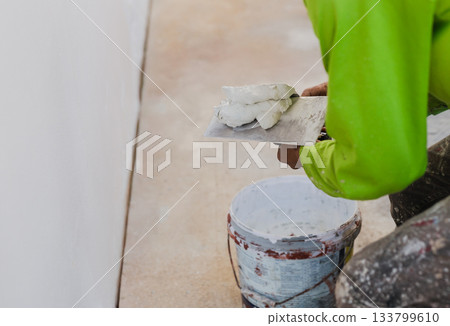 Worker with wall plastering tools renovating house. 133799610
