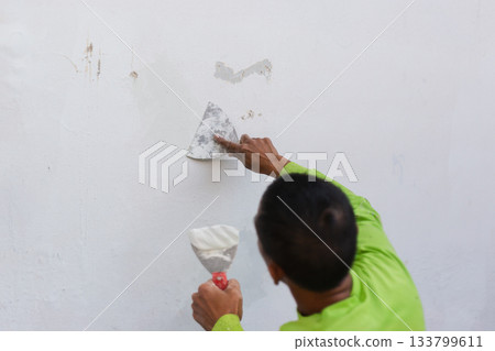 Painter's hand puttied wall using a paint trowel. 133799611