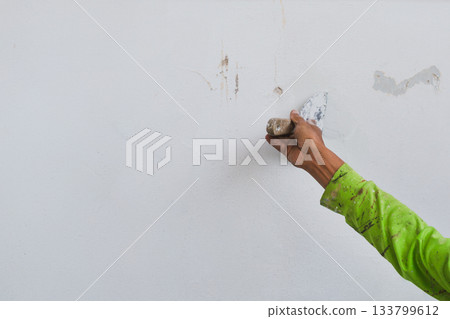 Man hand with trowel plastering a house wall outside. 133799612