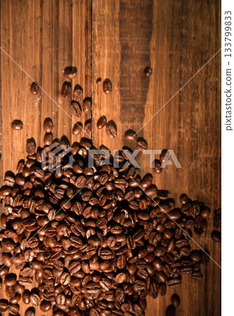 Dark roasted coffee beans are spilling across warm wooden tabletop in flat design Dark roasted coffee beans are spilling across warm wooden tabletop in flat design 133799833