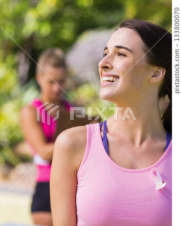 Close-up of smiling caucasian young woman with pink awareness ribbon on chest exercising in park Close-up of smiling caucasian young woman with pink awareness ribbon on chest exercising in park 133800070