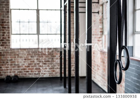 Flat design illustration showing gymnastic rings hanging from black beams in loft gym with window 133800938