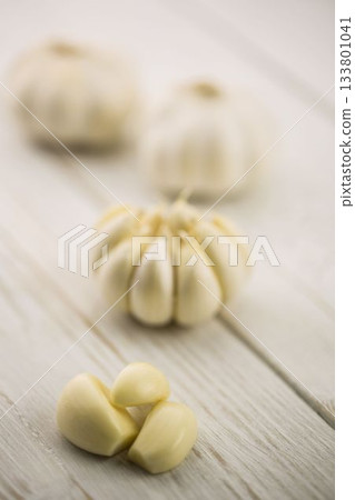 Garlic cloves and bulb on wooden surface Garlic cloves and bulb on wooden surface 133801041