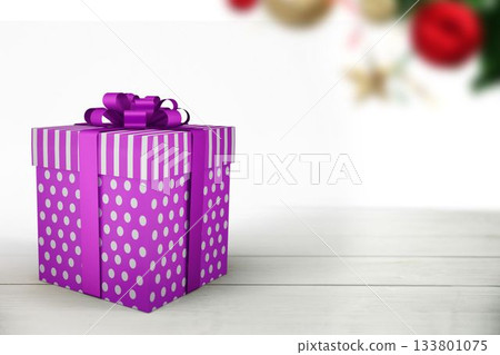 Flat design purple striped polka-dot gift box with ribbon bow resting on table with blurred baubles 133801075