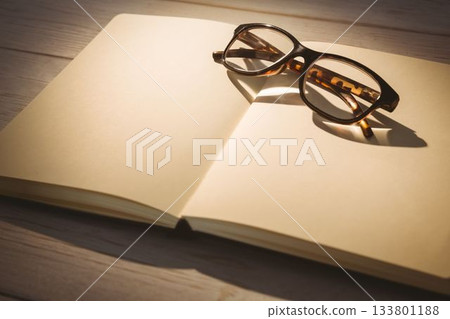 Eyeglasses on book at wooden desk 133801188