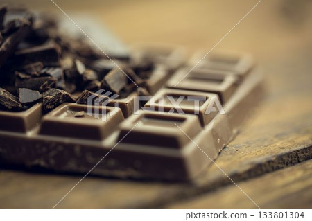 Milk chocolate bar with dark chocolate shards is resting in digital illustration on wooden tabletop 133801304
