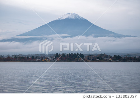 Lake Kawaguchi, Fujikawaguchiko, Minamitsuru District, Yamanashi, Japan, Snow capped Fuji mountain overlooking lake with village and clouds in the morning Lake Kawaguchi, Fujikawaguchiko, Minamitsuru District, Yamanashi, Japan, Snow capped Fuji mountain overlooking lake with village and clouds in the morning 133802357