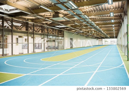 Multi-lane running track is curving inside flat design sports hall with glass partition wall 133802569