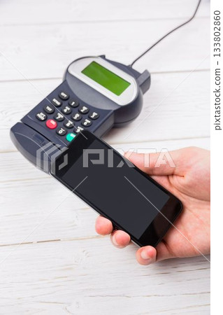 Flat design showing smartphone hovering above card reader on white tabletop for contactless payment Flat design showing smartphone hovering above card reader on white tabletop for contactless payment 133802860