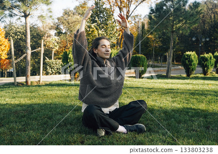 Peaceful Woman Meditating Outdoors in Sunny Autumn Park Peaceful Woman Meditating Outdoors in Sunny Autumn Park 133803238