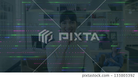 Smiling woman in office with colorful digital glitch image overlay Smiling woman in office with colorful digital glitch image overlay 133803392