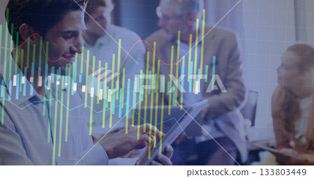 Tapping executive using tablet in boardroom as colleagues observing with stock overlay, copy space Tapping executive using tablet in boardroom as colleagues observing with stock overlay, copy space 133803449