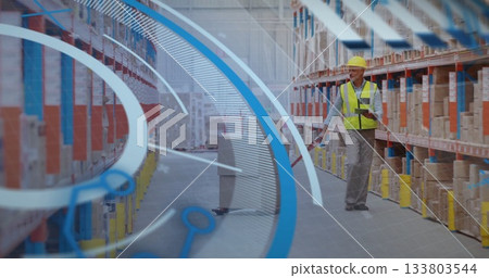 Pushing manual pallet jack male warehouse worker checking tablet in aisle, with boxes, copy space 133803544