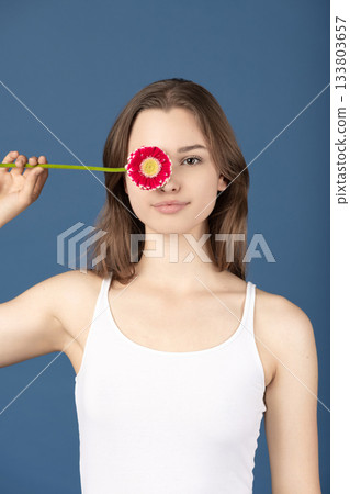 Beautiful woman covering her eye with purple flower Beautiful woman covering her eye with purple flower 133803657