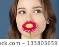 Beautiful woman covering her mouth with purple flower 133803659