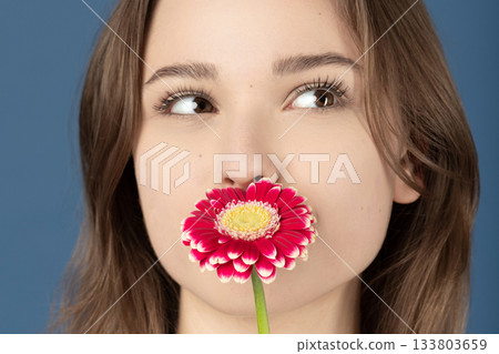Beautiful woman covering her mouth with purple flower 133803659
