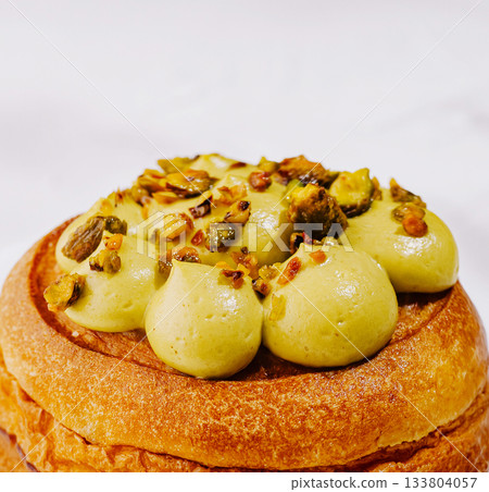 Delicious pastry topped with creamy pistachio mousse and crushed nuts Delicious pastry topped with creamy pistachio mousse and crushed nuts 133804057