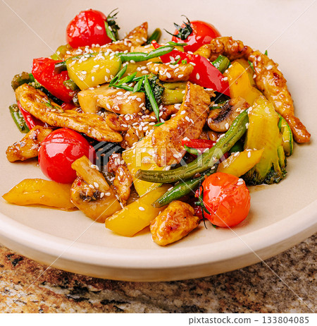Colorful vegetable stir-fry with chicken and sesame on a marble countertop 133804085