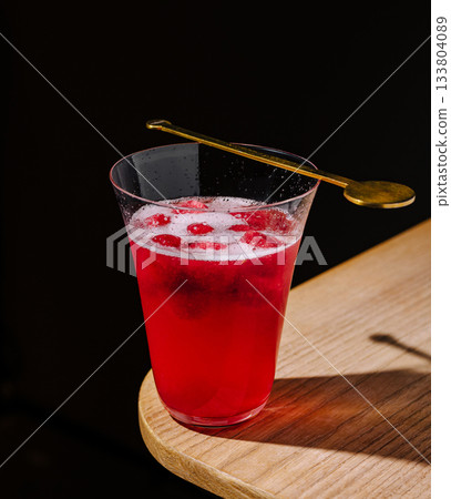 Refreshing red drink served in a stylish glass on a wooden table 133804089