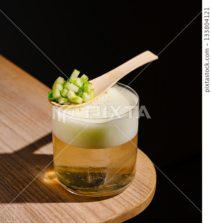 Refreshing drink with cucumber garnish served on a wooden table Refreshing drink with cucumber garnish served on a wooden table 133804121