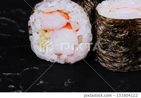 Fresh sushi rolls with shrimp and rice displayed on black surface Fresh sushi rolls with shrimp and rice displayed on black surface 133804122