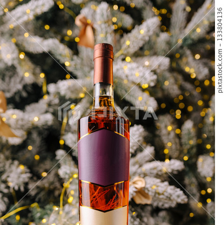 Festive whiskey bottle in front of a decorated Christmas tree 133804136