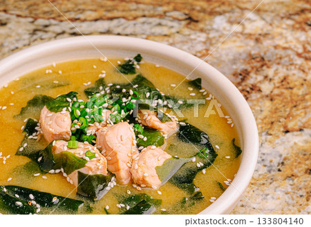 Delicious bowl of seaweed soup with fish chunks and herbs on granite surface Delicious bowl of seaweed soup with fish chunks and herbs on granite surface 133804140