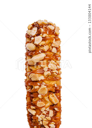 Delicious caramel-coated corn dog snack topped with crunchy peanuts 133804144