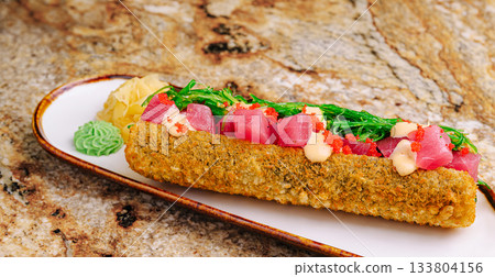 Unique sushi roll with fresh tuna and vibrant toppings on a plate 133804156
