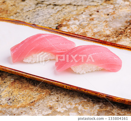 Fresh sushi featuring vibrant tuna slices on rice served on a traditional plate Fresh sushi featuring vibrant tuna slices on rice served on a traditional plate 133804161