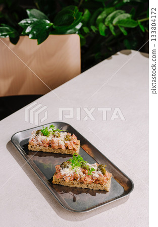 Delicious open-faced sandwiches served on a metallic tray in a cozy setting 133804172