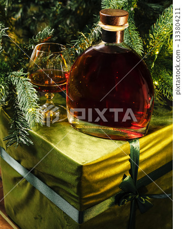 Holiday gift box with a bottle of whiskey and a glass in festive setting 133804211
